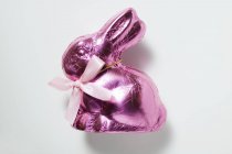 Coelho de chocolate em papel alumínio rosa — Fotografia de Stock
