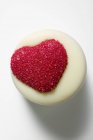 Крупный план белого шоколада с красным сердцем на белой поверхности — стоковое фото