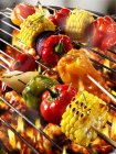 Vegetable kebabs on barbecue rack over fire flames — Stock Photo