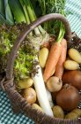 Соломенная корзина из свежих овощей и салата поверх ткани — стоковое фото