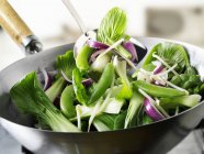 Verduras verdes en wok con fondo borroso - foto de stock