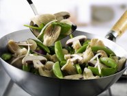 Legumes e cogumelos em wok e em espátula — Fotografia de Stock