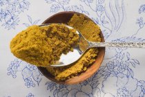 Poudre de curry dans un bol et sur une cuillère — Photo de stock