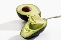 Hollowing out avocado with spoon — Stock Photo