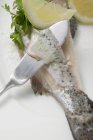 Removing trout skin with fish knife — Stock Photo
