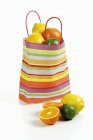 Citrus fruits in striped paper bag — Stock Photo