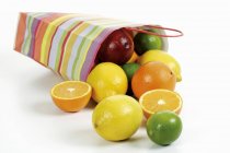 Vista close-up de saco de papel colorido de frutas cítricas no fundo branco — Fotografia de Stock