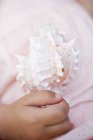 Крупный план обрезанный вид на детскую руку с помощью морской раковины — стоковое фото