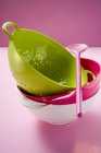 Closeup view of colored stacked colanders and pink cooking spoon — Stock Photo