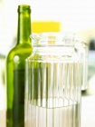Closeup view of white wine in a carafe near a green bottle — Stock Photo