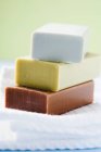 Closeup view of three piled bars of soap on folded towels — Stock Photo