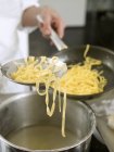 Cocinar poniendo pasta en la sartén - foto de stock