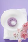 Повышенный вид мыла с пеной в белой миске на полотенце рядом с орхидеями — стоковое фото