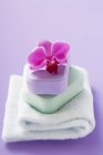 Vista de cerca de dos barras apiladas de jabón de color con orquídea en toalla doblada - foto de stock