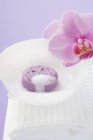 Jabón con espuma en tazón blanco sobre toalla por flor cortada orquídea - foto de stock