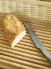 Piece of baguette with knife — Stock Photo