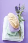 Vue surélevée de brosse et barres empilées de savon coloré sur serviette avec brin de lavande — Photo de stock