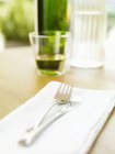 Closeup view of knife and fork on a fabric napkin near drinks on table — Stock Photo