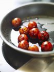 Freír tomates cóctel con vinagre balsámico en sartén - foto de stock