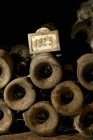 Vieilles bouteilles de vin empilées avec étiquette année et poussière dans la cave à vin — Photo de stock