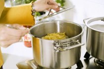 Mulher cozinhar macarrão em panela — Fotografia de Stock