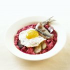 Labskaus - Соленая сельдь, свекольное пюре, лук и яйцо на белой тарелке — стоковое фото
