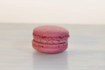 Closeup view of one raspberry macroon on white surface — Stock Photo