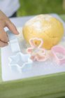 Closeup cropped view of child hand by dough ball and biscuit cutters — Stock Photo