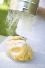 Closeup view of sprinkling dough with sifted flour — Stock Photo