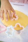 Cropped view of child hand cutting biscuit dough — Stock Photo