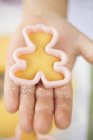 Closeup cropped view of child hand holding bear-shaped biscuit cutter with dough — Stock Photo