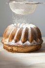 Closeup view of sprinkling marbled Gugelhupf with icing sugar — Stock Photo