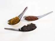 Primo piano vista di tre paste di spezie asiatiche su cucchiai — Foto stock