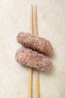 Closeup view of dumplings in coconut flakes on chopsticks — Stock Photo
