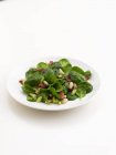 Salade d'épinards avec bacon et pignons de pin sur assiette blanche — Photo de stock