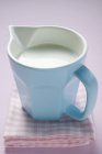 Milk in small jug on tea towel — Stock Photo