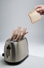 Руки, доходящие до тостера — стоковое фото