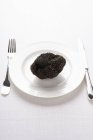 Fresh black truffle on white plate — Stock Photo