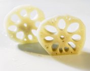 Two slices of lotus root on white surface — Stock Photo