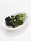 Brokkoli mit Mandelsplittern auf weißem Teller über weißer Oberfläche — Stockfoto