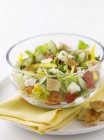 Греческий салат с кускусом в белой миске над тарелкой — стоковое фото
