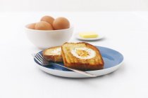 Uova fritte su pane tostato con uova crude e burro — Foto stock