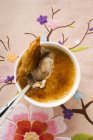 Top view of Creme brulee with spoon in bowl on embroidered cloth — Stock Photo