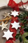 Cinnamon stars and sprigs of holly — Stock Photo