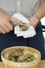 Ausgeschnittene Ansicht eines Mannes, der Auster mit Messer auf Tuch öffnet — Stockfoto