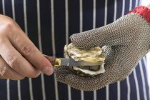 Closeup cropped view of hands shucking oyster — Stock Photo