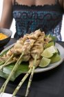 Closeup cropped view of woman holding tray of satay and dip — Stock Photo