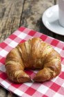 Croissant on checked cloth — Stock Photo