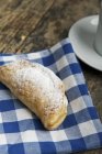 Closeup view of apple turnover dusted with icing sugar on checkered cloth — Stock Photo