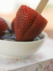 Closeup view of strawberry on stick in chocolate sauce — Stock Photo